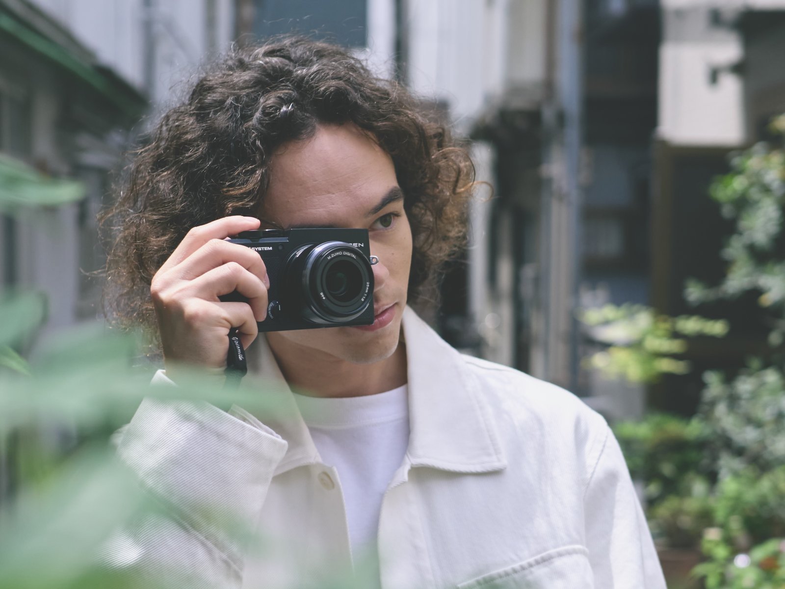 カメラ「OM SYSTEM PEN」をもつ男性の写真